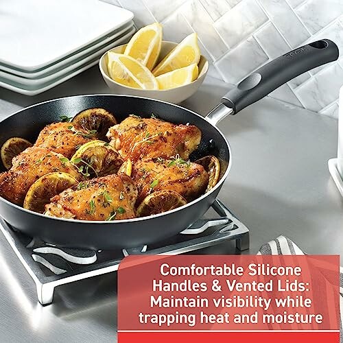 Cooked chicken thighs with lemon slices in a frying pan on a stove.