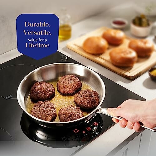 Person cooking burgers in a frying pan on induction stove.