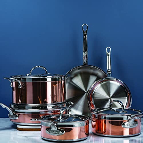 Copper and stainless steel cookware set on blue background