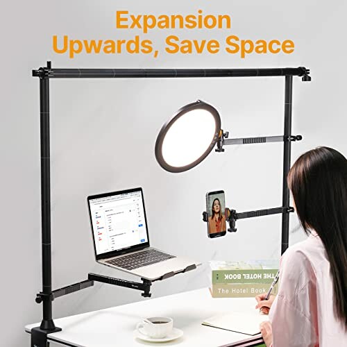 Person using a desk mount with laptop, phone, and ring light.