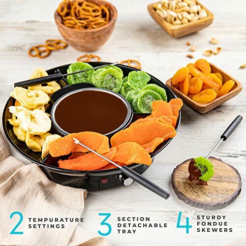 Electric fondue set with assorted dried fruits, nuts, and pretzels.