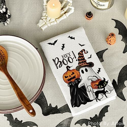 Halloween-themed kitchen setup with ghost and pumpkin towel, bats, and candles.