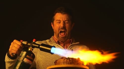 Man using a blowtorch to sear a steak.