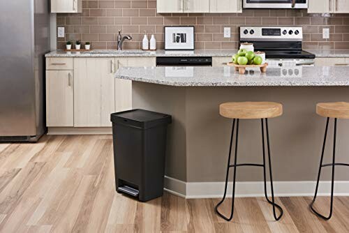 Modern kitchen with a black trash can and bar stools.