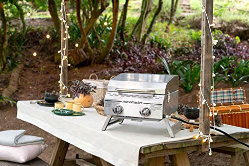 Portable grill on picnic table in a wooded area.
