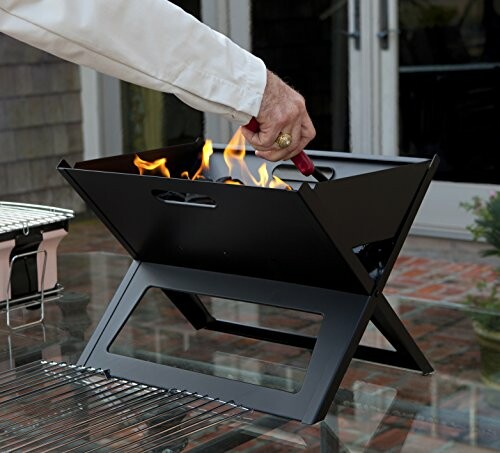 Person using a portable folding grill with flames.