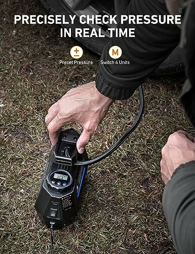 Person using portable tire inflator on grass with digital display.