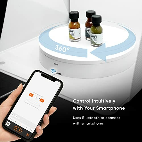 Smartphone controlling a rotating display with bottles on top.