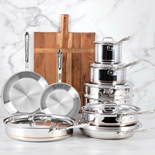 Set of stainless steel pots and pans with wooden cutting board