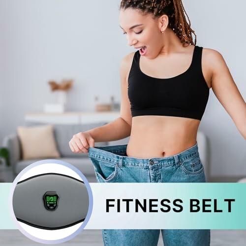 Woman amazed by fitness belt results, wearing loose jeans.